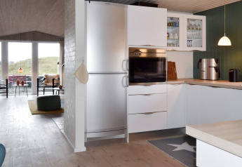 Cucina moderna con armadietti bianchi, forno e frigorifero in una casa vacanze a Fanø, Danimarca.