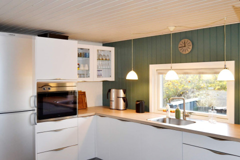 Cucina moderna nella 'casa vacanze per 6 persone a Fanø', Danimarca, con armadi bianchi e finestra ampia.