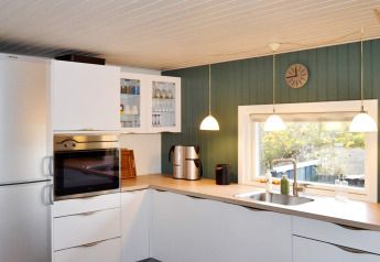 Cucina moderna nella 'casa vacanze per 6 persone a Fanø', Danimarca, con armadi bianchi e finestra ampia.