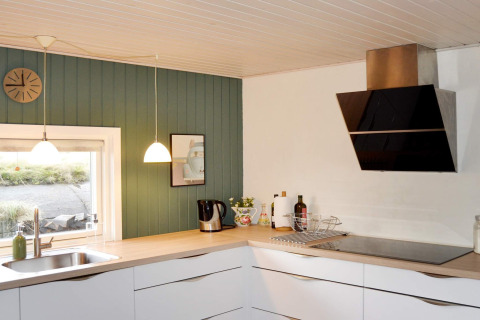Cucina moderna in casa vacanza per 6 persone a Fanø, Danimarca, con mobili bianchi e parete verde.