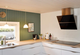 Cucina moderna in casa vacanza per 6 persone a Fanø, Danimarca, con mobili bianchi e parete verde.