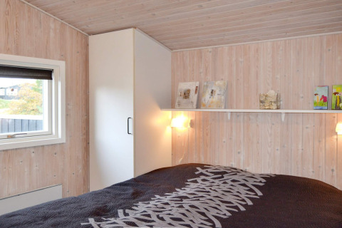 Schlafzimmer im '6-Personen-Ferienhaus in Fanø', Dänemark, mit hellem Holz, Regal und Fenster mit Aussicht.