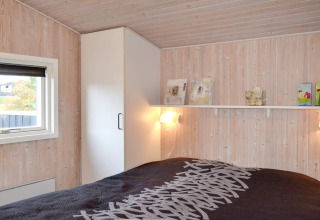Schlafzimmer im '6-Personen-Ferienhaus in Fanø', Dänemark, mit hellem Holz, Regal und Fenster mit Aussicht.