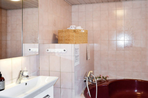 Badezimmer mit Spiegel, Waschbecken, Korb und weinroter Badewanne in Ferienhaus auf Fanø, Dänemark.