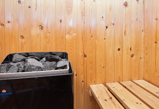 Innenansicht einer Sauna mit Holzvertäfelung, Saunaofen und Bank in einem Ferienhaus in Fanø, Dänemark.