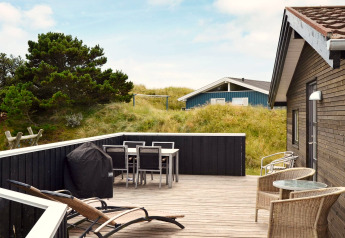 Terrasse extérieure d'une maison de vacances pour 6 personnes à Fanø, Danemark, avec mobilier, BBQ et dunes.