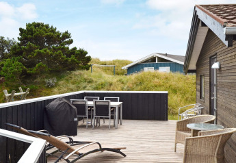 Terrasse eines 6-Personen-Ferienhauses in Fanø, Dänemark, mit Gartenmöbeln, Grill und Dünenblick.