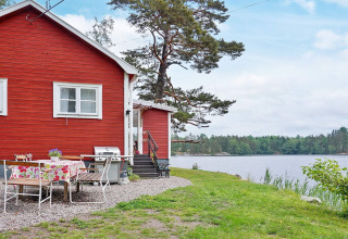 Casa vacanze rossa sul lago ad Åkersberga, Svezia, con area pranzo esterna e vista panoramica.