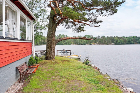 Scenic view from holiday lodge in Åkersberga, Sweden with red siding, bench, tree, and boats.