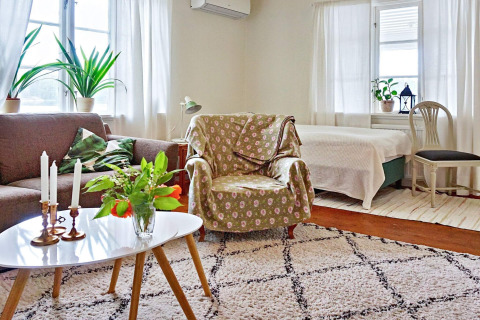 Wohnzimmer eines Ferienhauses in Åkersberga, Schweden, mit Sofa, Sessel, Pflanzen und Tageslicht.