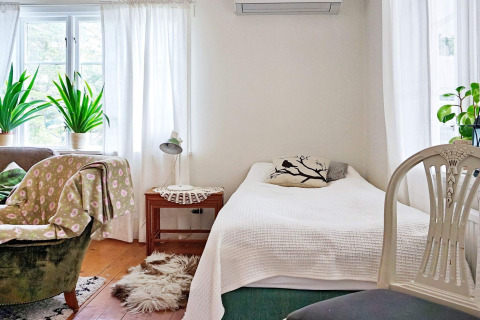 Helles Schlafzimmer im Ferienhaus in Åkersberga, Schweden, mit Pflanzen, Sessel und Tageslicht.