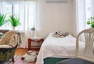 Helles Schlafzimmer im Ferienhaus in Åkersberga, Schweden, mit Pflanzen, Sessel und Tageslicht.