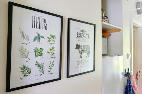 Due quadri incorniciati in cucina: uno con erbe aromatiche illustrate, l'altro con tagli di manzo.