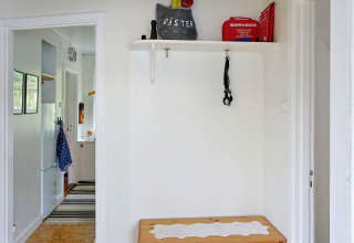 Eingangsbereich eines Ferienhauses in Åkersberga, Schweden, mit Sitzbank, Regal und Erste-Hilfe-Set.