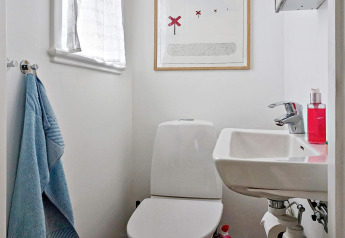 Kleines Badezimmer mit WC, Waschbecken, blauem Handtuch und Kunstbild im 5-Personen-Ferienhaus Åkersberga.