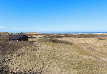 Chalet de vacances entouré de dunes avec vue sur la mer et ciel bleu à Bindslev, Danemark.