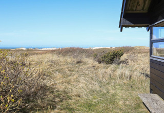 Blick von einem Ferienhaus in Bindslev, Dänemark, auf Dünen, Graslandschaft und das Meer.