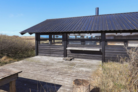 Udendørs terrasse og sort træchalet ved 4 personers feriehus i Bindslev, Danmark, med naturskøn udsigt.