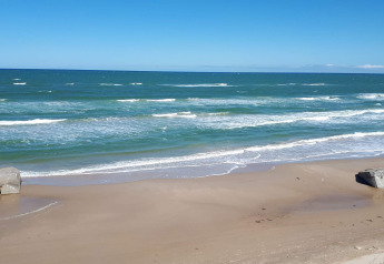 Blick auf das Meer, den Strand und Bunker bei einer Glamping-Unterkunft an einem sonnigen Tag.