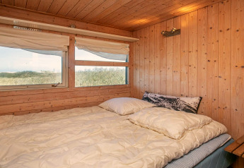 Camera da letto con letto matrimoniale e pareti in legno nello chalet 'Casa vacanze 4 persone a Bindslev', Danimarca.