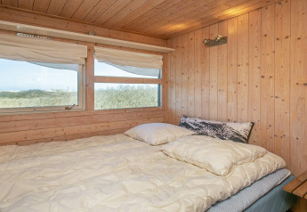 Dormitorio con cama doble y paredes de madera en el chalet 'Casa de vacaciones para 4 personas en Bindslev', Dinamarca.