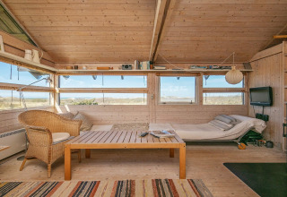 Gemütliches Wohnzimmer in einem Ferienhaus in Bindslev, Dänemark, mit Holzverkleidung und Naturblick.