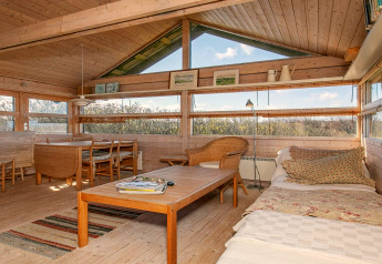 Living area with Scandinavian wood design, large windows and dining table in 4-person holiday home, Bindslev.
