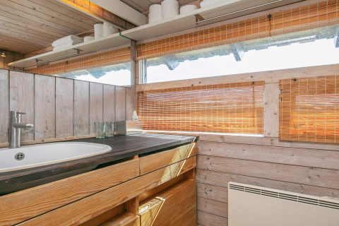Holzverkleidetes Badezimmer mit Waschbecken, Holzschränken und Raffrollos in Chalet in Bindslev, Dänemark.