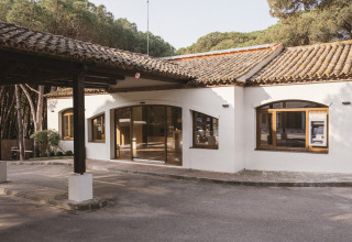 Entrada al parque vacacional Wecamp Cala Montgó en Cataluña, España, rodeada de pinos y naturaleza.