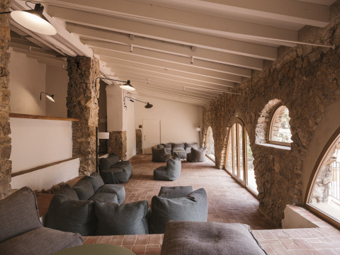 Acogedora sala con paredes de piedra y pufs en Wecamp Cala Montgó, un parque vacacional en Cataluña, España.