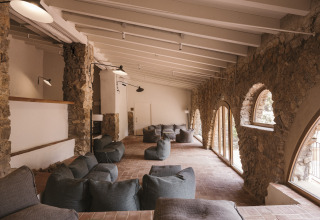 Gezellige lounge met natuurstenen muren en zitzakken bij Wecamp Cala Montgó vakantiepark in Catalonië, Spanje.