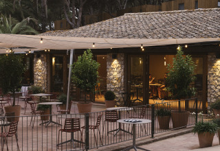Außenterrasse von Wecamp Cala Montgó in Katalonien, Spanien, mit Tischen, Stühlen und Lichterketten.