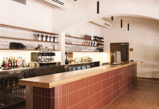 Bar moderno con soffitto in legno e piastrelle rosse al Wecamp Cala Montgó, parco vacanze in Catalogna, Spagna.