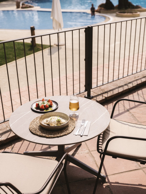 Tavolo all'aperto con pasto e bevanda presso la piscina di Wecamp Cala Montgó, villaggio vacanze in Catalogna.