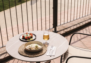 Udendørs cafébord med måltid og drink ved poolen i Wecamp Cala Montgó feriepark, Catalonien, Spanien.