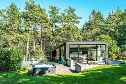 Modernes Ferienhaus für 8 Personen in Ebeltoft mit Whirlpool und Waldblick, umgeben von Bäumen.