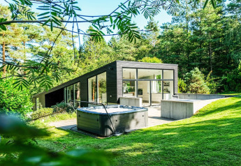 Casa vacanze moderna a Ebeltoft, Danimarca, con ampie vetrate, vasca idromassaggio e natura verdeggiante.