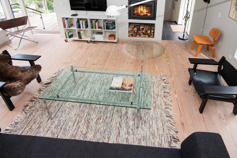 Modernes Wohnzimmer im 8-Personen-Ferienhaus in Ebeltoft, Dänemark mit Kamin und Glas-Couchtisch.