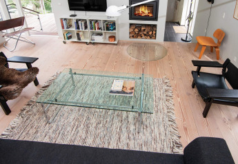 Sala moderna en casa vacacional para 8 personas en Ebeltoft, Dinamarca con chimenea y mesa de vidrio.
