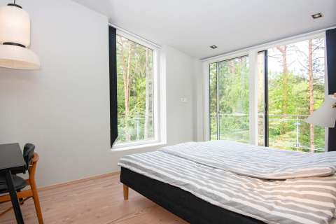 Schlafzimmer mit modernen Möbeln, großen Fenstern und Waldblick im 8-Personen-Ferienhaus in Ebeltoft, Dänemark.