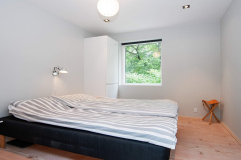 Schlafzimmer im 8-Personen-Ferienhaus in Ebeltoft, Dänemark, mit Doppelbett, Schrank und Waldblick.