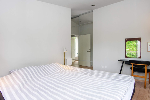 Schlafzimmer im 8-Personen-Ferienhaus in Ebeltoft, Dänemark, mit modernem Design und Gartenblick.
