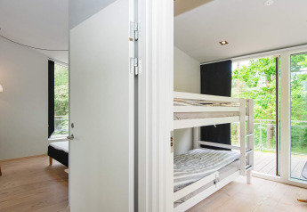 Chambre lumineuse avec lits superposés et grandes fenêtres dans maison de vacances 8 personnes à Ebeltoft.