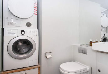Modernes Badezimmer in Ebeltoft mit Waschmaschine, Trockner, Toilette und Spiegel in heller Einrichtung.