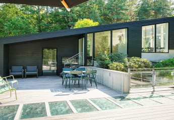 Maison de vacances moderne à Ebeltoft, Danemark, avec terrasse spacieuse, mobilier extérieur et vue sur la forêt.