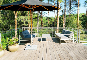 Terrasse extérieure d’une maison de vacances 8 personnes à Ebeltoft, Danemark, avec parasol et canapés.