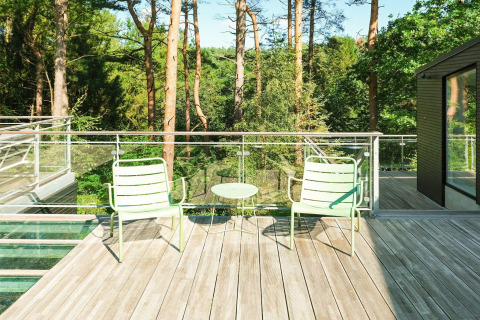 Sonnige Terrasse mit zwei hellgrünen Stühlen und kleinem Tisch in Waldnähe beim Ferienhaus in Ebeltoft.