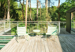 Sonnige Terrasse mit zwei hellgrünen Stühlen und kleinem Tisch in Waldnähe beim Ferienhaus in Ebeltoft.