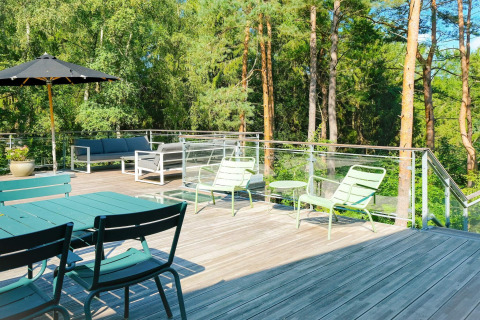 Große Holzterrasse mit Gartenmöbeln und Glasgeländer am Waldrand beim '8-Personen-Ferienhaus in Ebeltoft', Dänemark.