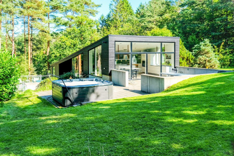 Modernes Ferienhaus in Ebeltoft, Dänemark, mit großen Fenstern, Whirlpool und üppigem grünen Garten.